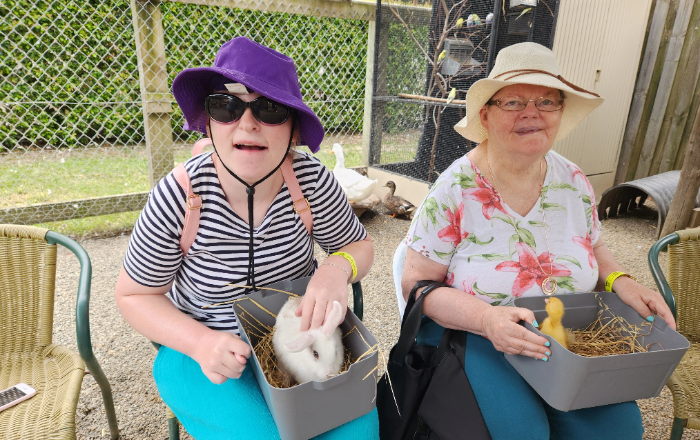 Two people sitting and patting small animals