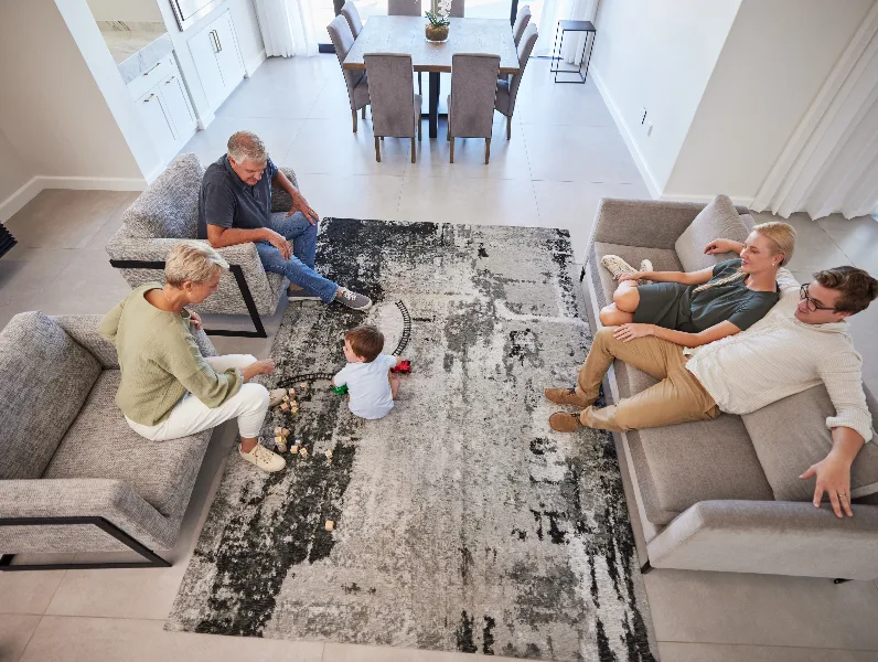 People on couch with child, grey carpet, modern home