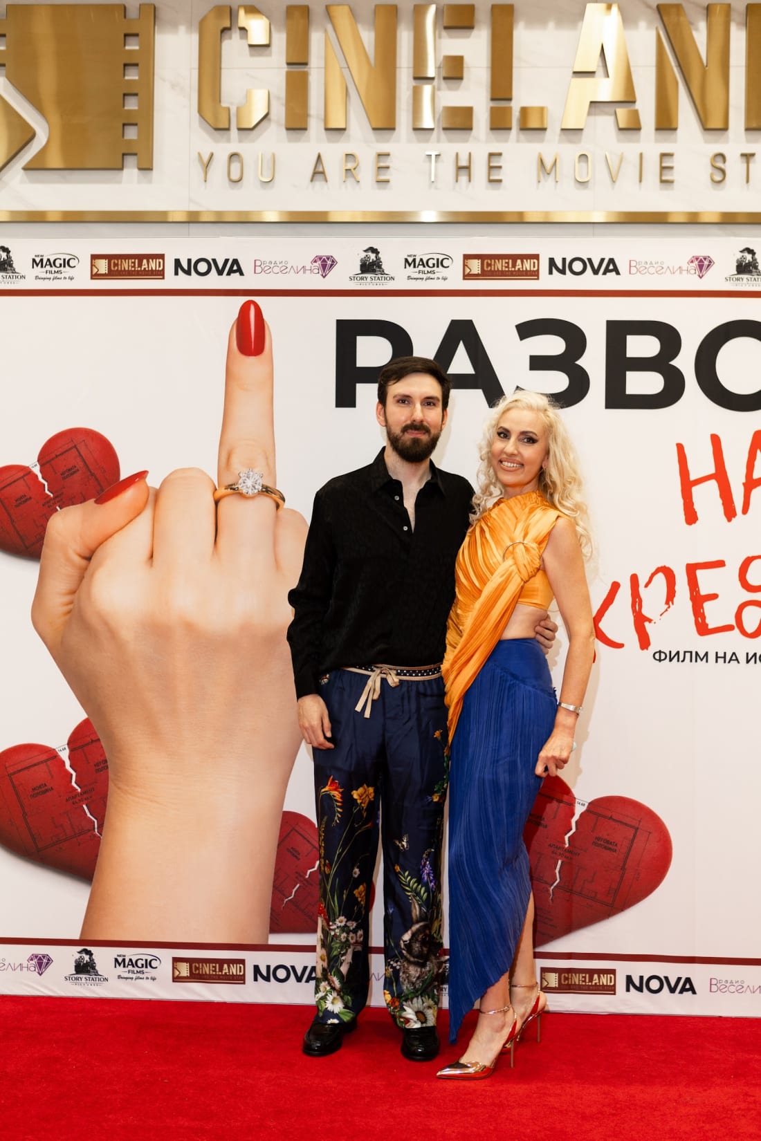 Двама гости пред плаката на филма — галапремиера на „Развод на кредит“, 23 юли 2026 г.