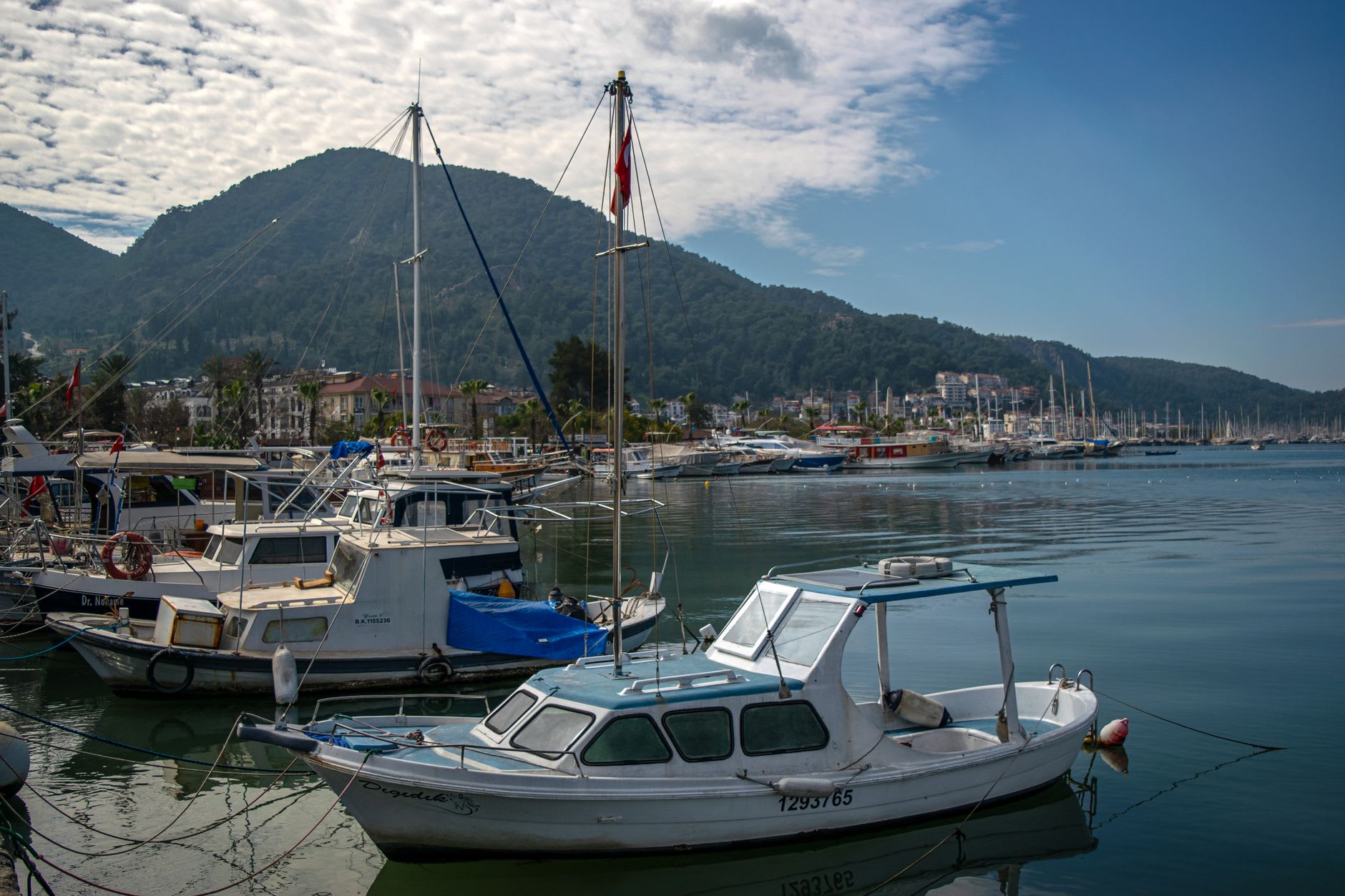 Goélettes ancrées dans l'une des baies insulaires de Göcek, eau turquoise entourée de falaises couvertes de pins sous un ciel bleu dégagé