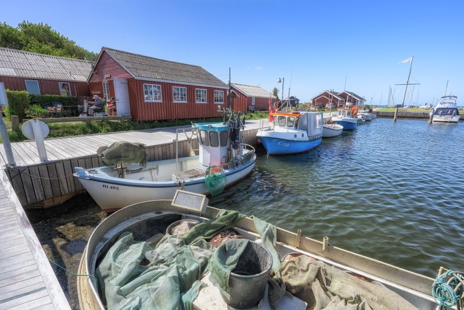 Weathered wooden fishing harbor on Kumlinge with drying herring nets and small boats moored against a granite shoreline