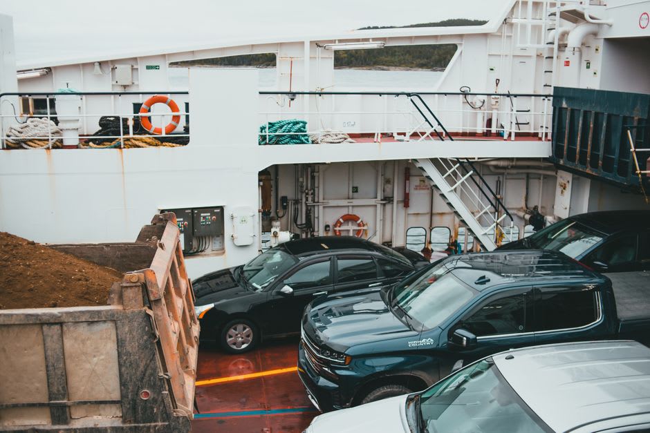 Cars and trucks loading onto a large white ferry at the harbor terminal of Långnäs under a bright midday sky
