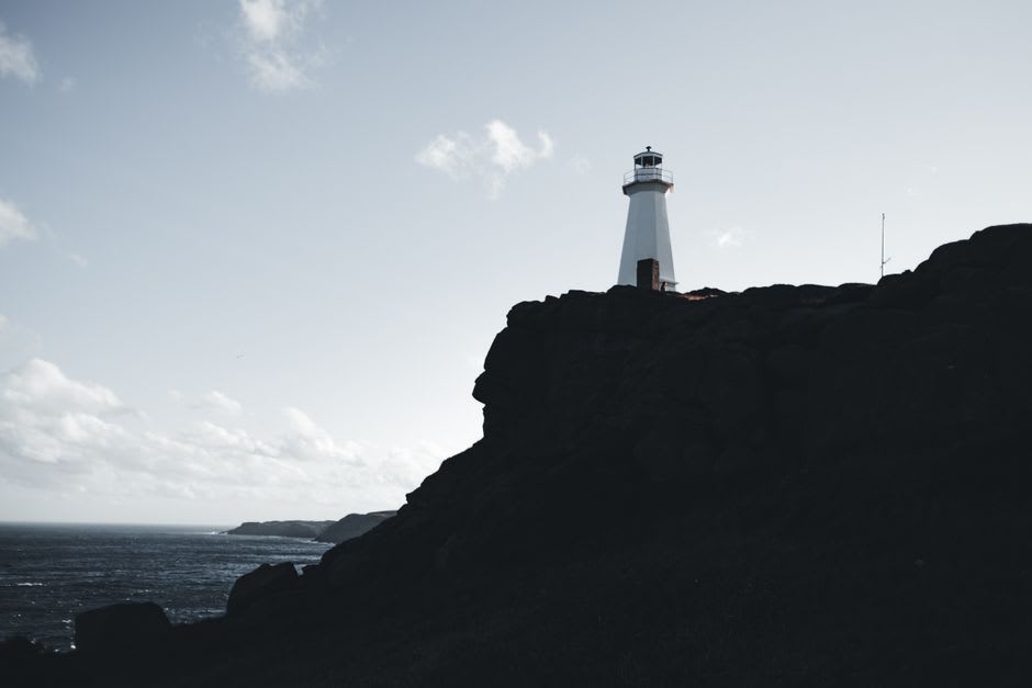 Rocky, treeless shoreline of Signilskär with waves breaking against smooth granite and the white lighthouse visible in the distance