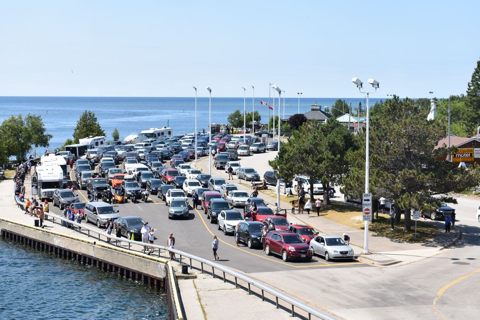 Coches en cola en un pequeño embarcadero de grava en Simskäla esperando para embarcar en un transbordador de cable a través de un estrecho canal