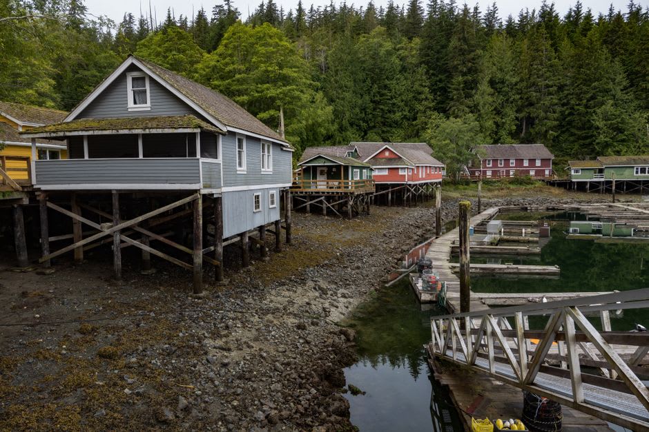 A Huna Tlingit tribal house at Bartlett Cove with carved totem figures against a backdrop of forest