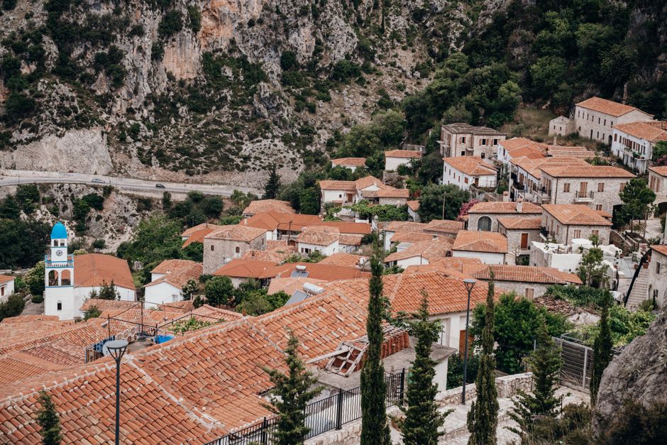 El antiguo pueblo de piedra de Dhërmi construido en la ladera con montañas alzándose detrás