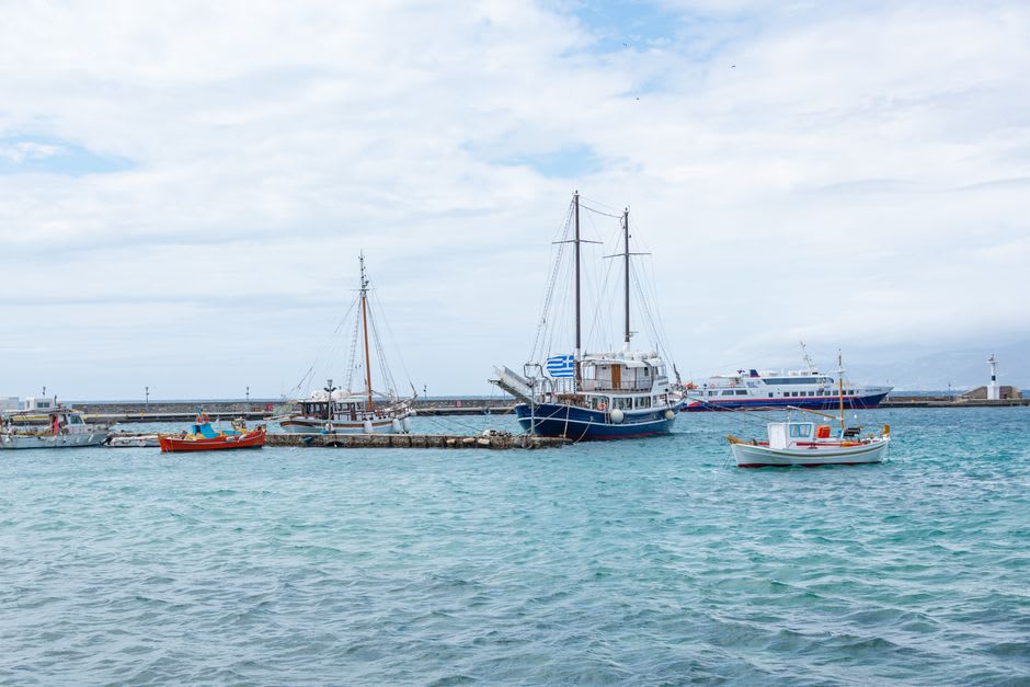 Fishing boats moored in Himarë's small harbor with the old town rising on the hill above
