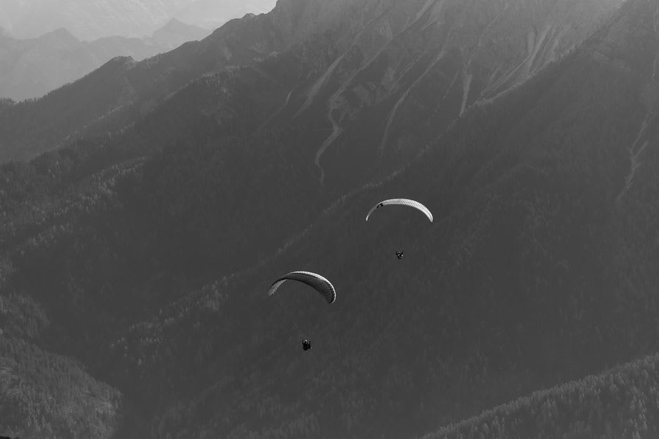 Un parapentiste décollant depuis la crête du col de Llogara avec une forêt de pins en contrebas