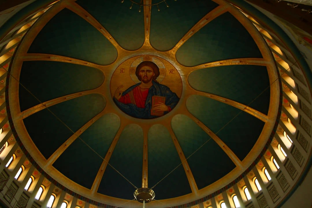 Faded but detailed biblical fresco paintings covering the interior walls and ceiling of a church in Voskopojë