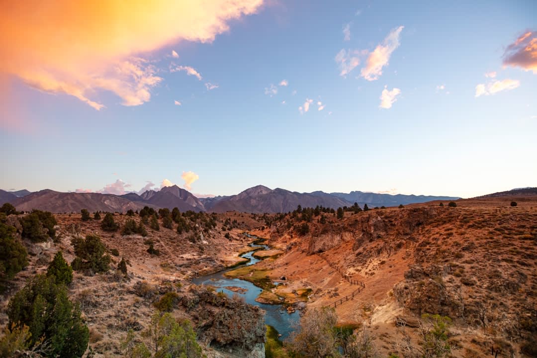 The Milk River winding between eroded hoodoo formations at dusk, the sandstone glowing orange in the last light