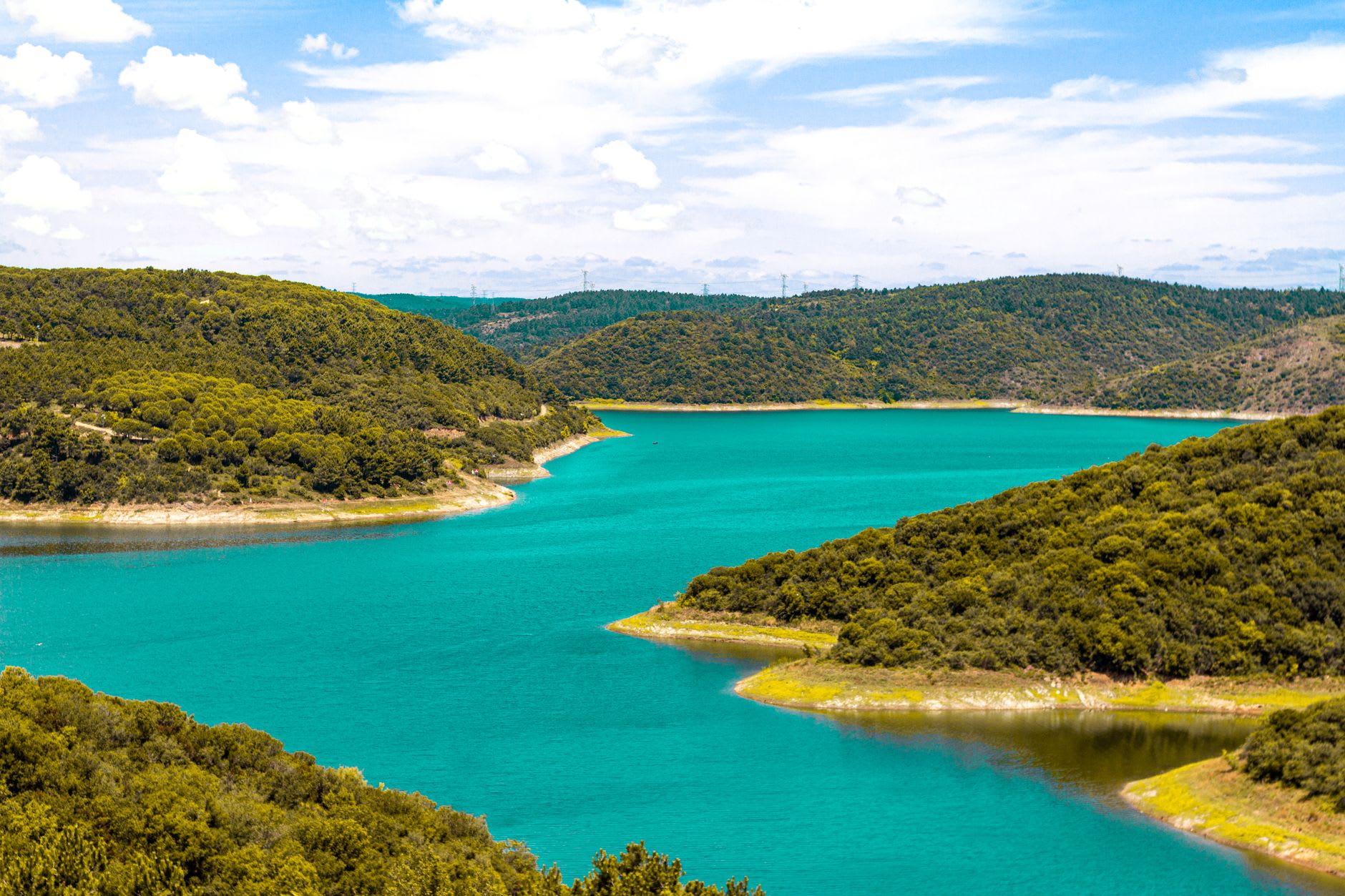 A small wooden boat moored on the red clay bank of the Alqueva reservoir at golden hour