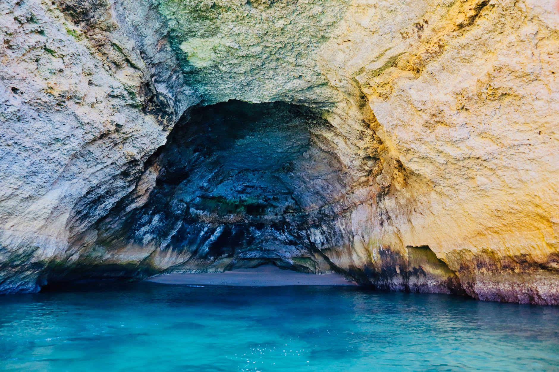 Algar Seco rock formations at Carvoeiro — cathedral-like golden sandstone columns and arches with turquoise pools at their base