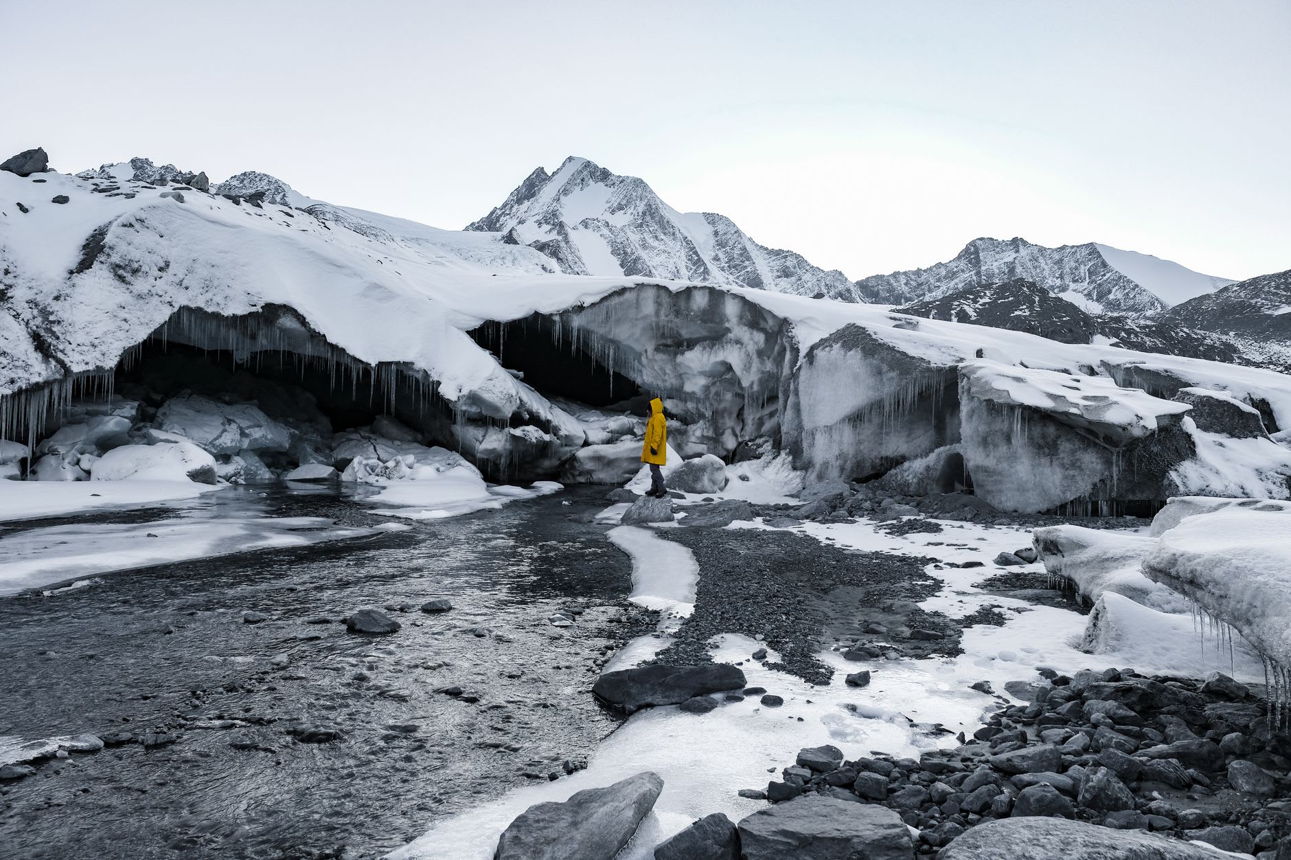 The milky Aktru River flowing down the valley from the glacier with dark scree slopes on both sides