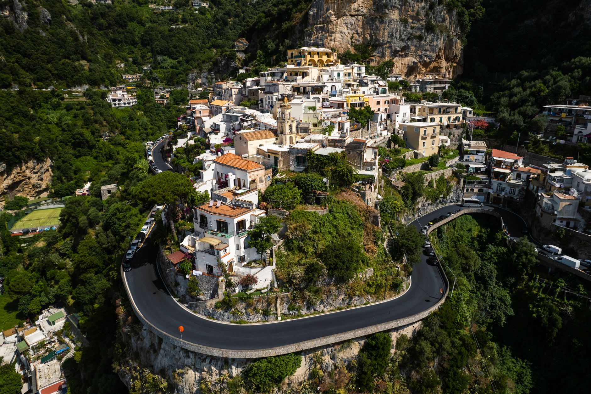 The shaded arched lanes of Amalfi's old town with laundry strung above and a vendor stacking ceramic goods in a doorway