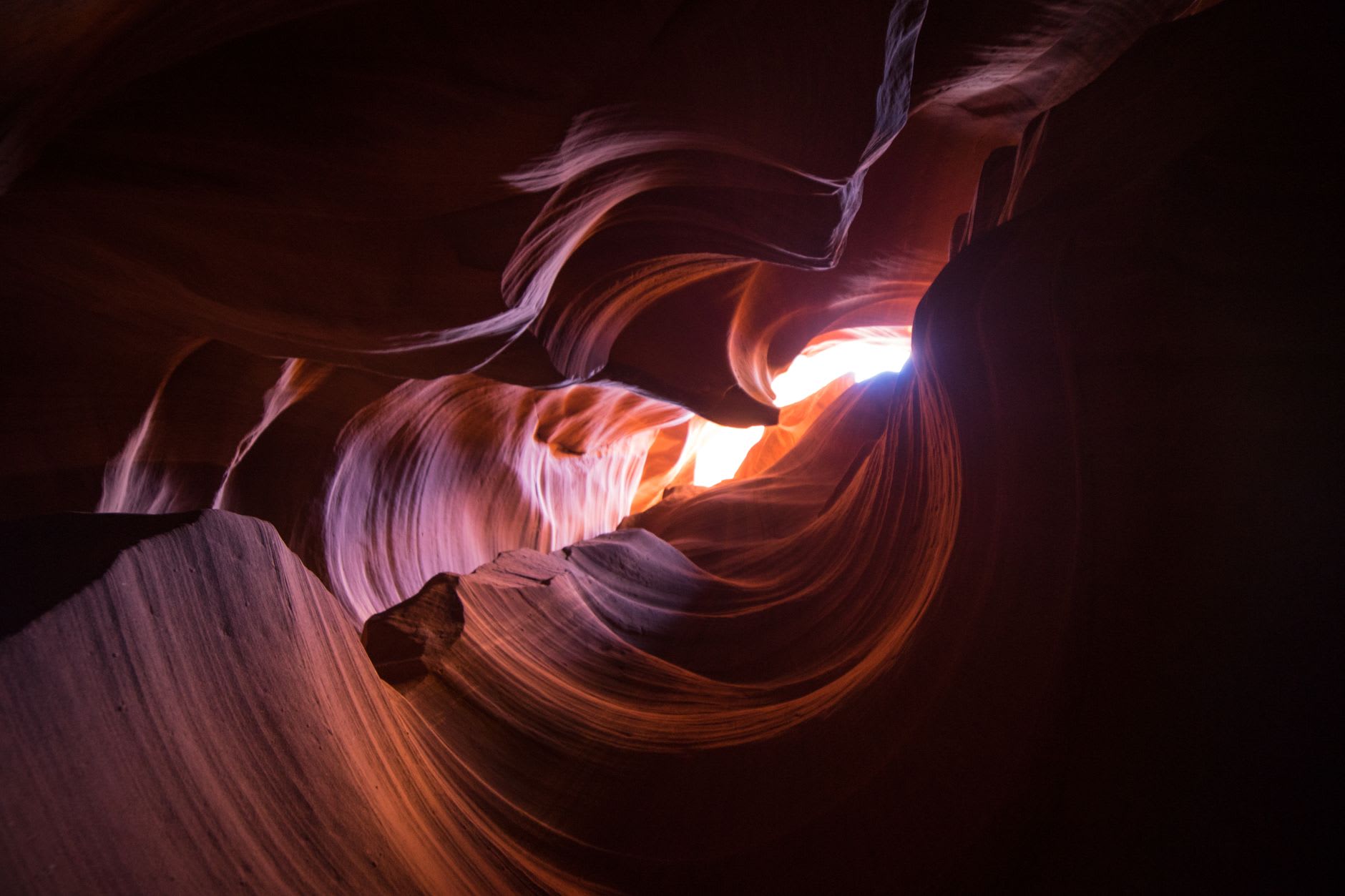 Antelope Canyon's narrow passage with its wave-carved sandstone walls glowing in warm pink and orange light