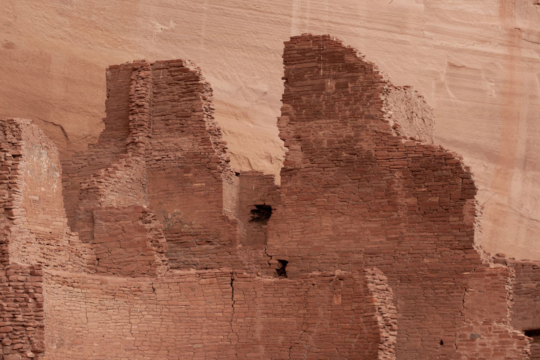 A Navajo guide's open Jeep parked on the sandy canyon floor beside ancient handprints and figures painted on the rock wall