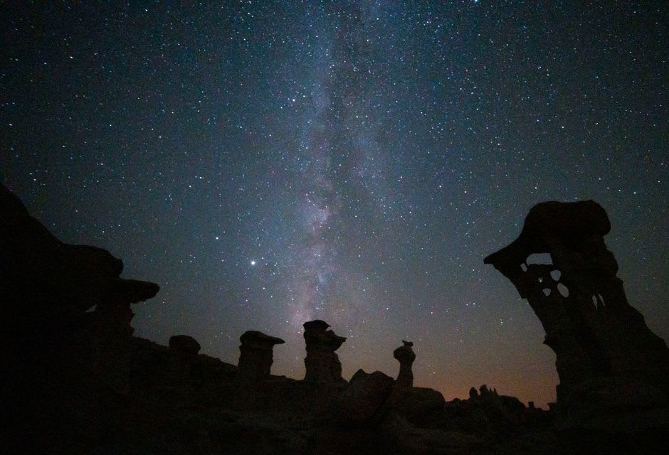 The Milky Way arcing over the dark silhouette of a Chaco great house at night