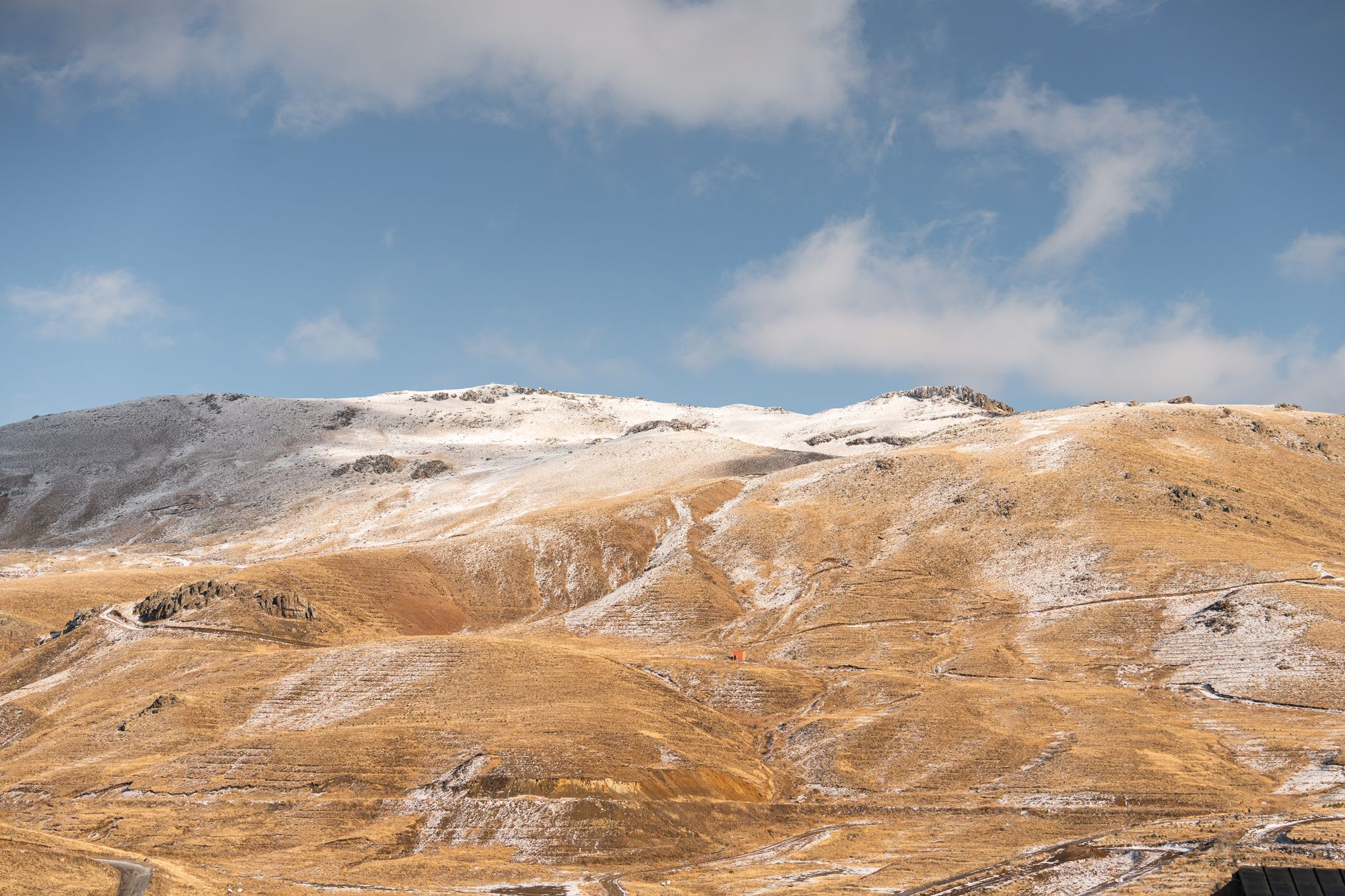A skier cutting through fresh powder on the upper slopes of Erciyes, with the volcanic summit ridge and an infinite blue sky behind