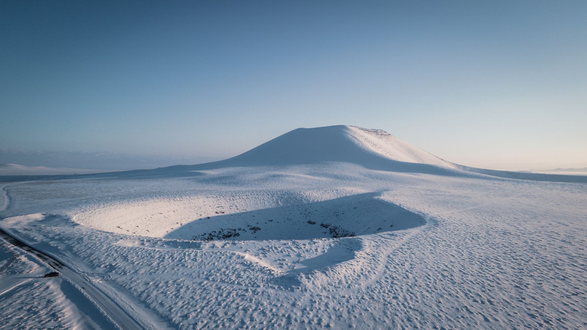 The white mineral-encrusted shoreline of Meke Crater Lake at low water level, with the flat Karapınar steppe and distant wheat fields behind