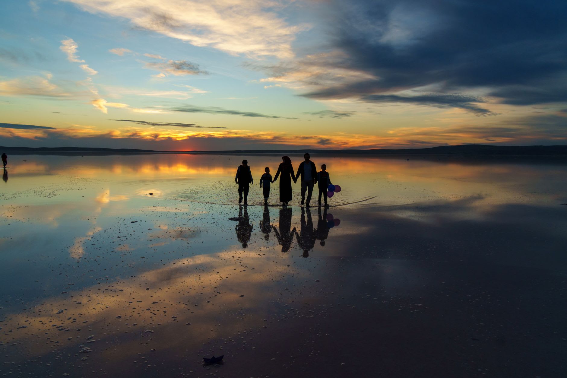 The edge of the salt crust dissolving into shallow orange-tinted brine at Tuz Gölü, with the flat horizon and pale sky