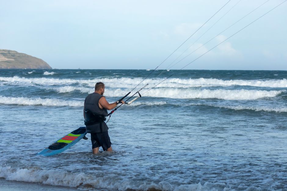 Kitesurfer riding the swell off the beach at Cabo Ledo with red cliffs in the background
