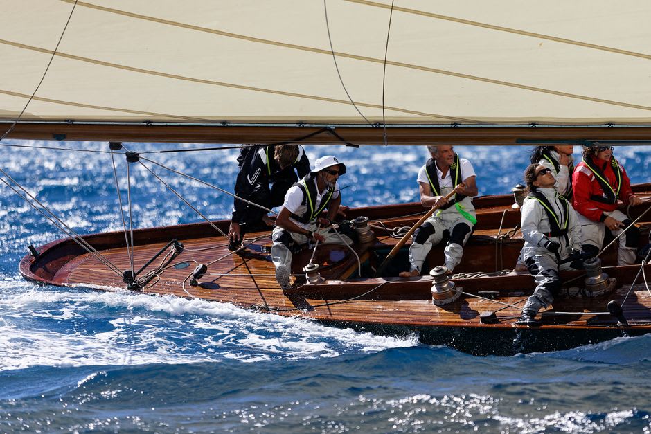 Sailors coiling ropes on the deck of a classic wooden yacht docked at English Harbour