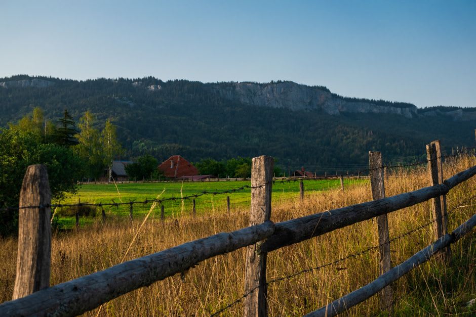 A split-rail fence and old farmstead structure along a grassy overlook on the Blue Ridge Parkway