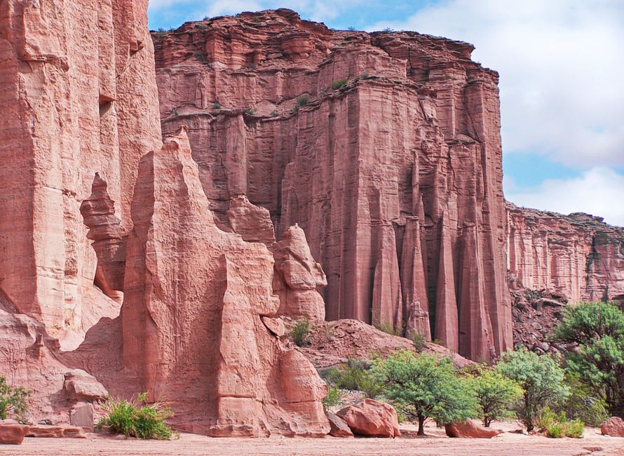 Parois abruptes de grès rouge s'élevant au-dessus d'une route de terre étroite dans le parc national de Talampaya