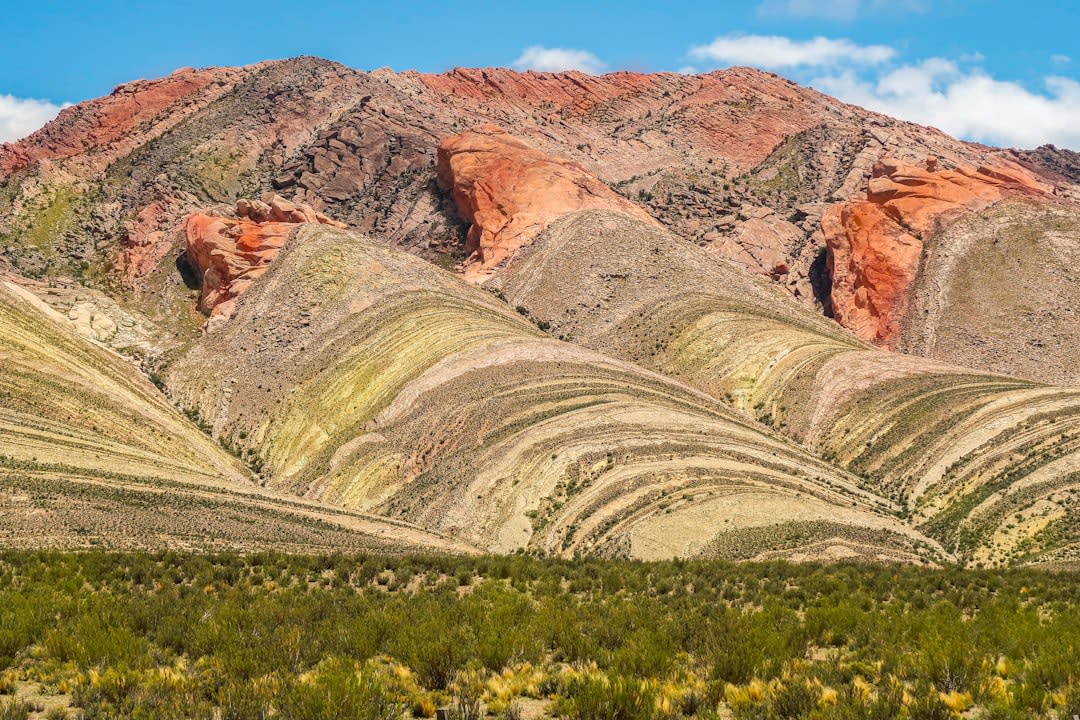 Passengers standing beneath the towering La Polvorilla viaduct at 4,220 meters, surrounded by barren Puna landscape