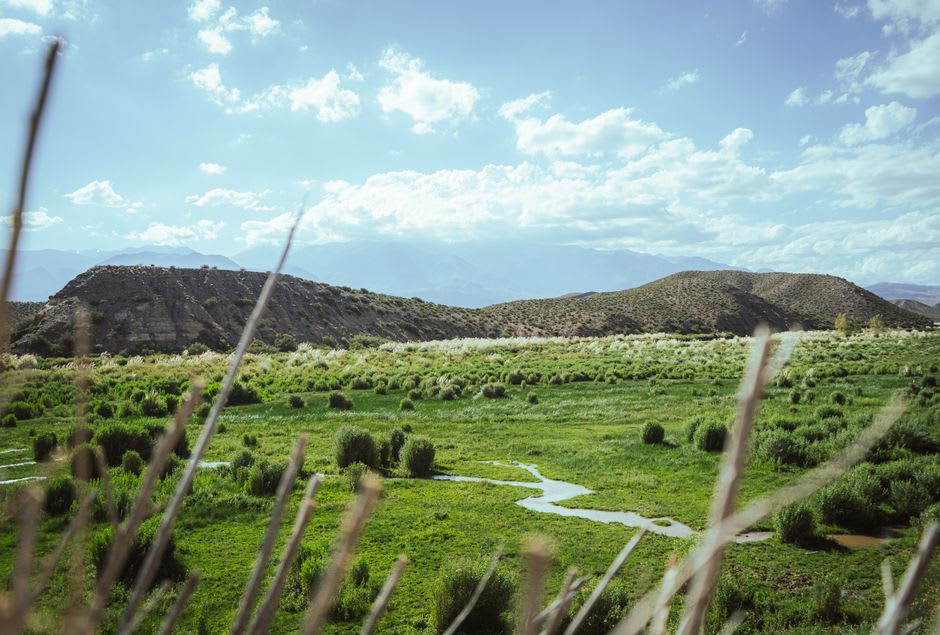 Red sandstone rock formations rising from pale scrubland in the wide Uspallata valley