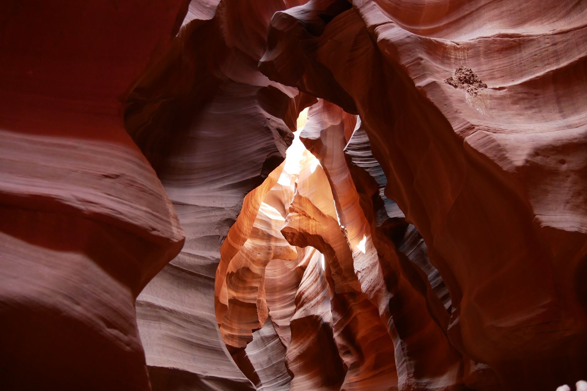 A narrow passage in Lower Antelope Canyon where the walls almost touch overhead, light glowing amber between them