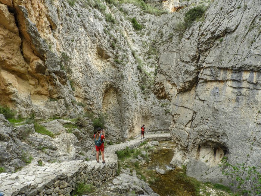 Hikers walking a narrow trail between towering rhyolite rock columns in Echo Canyon
