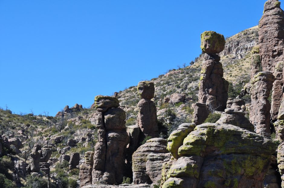 A balanced boulder perched precariously atop a narrow rock spire against a blue Arizona sky