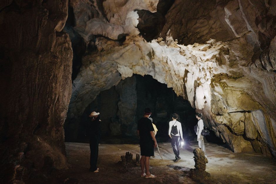 A guided tour group walking through the dimly lit passages of Kartchner Caverns
