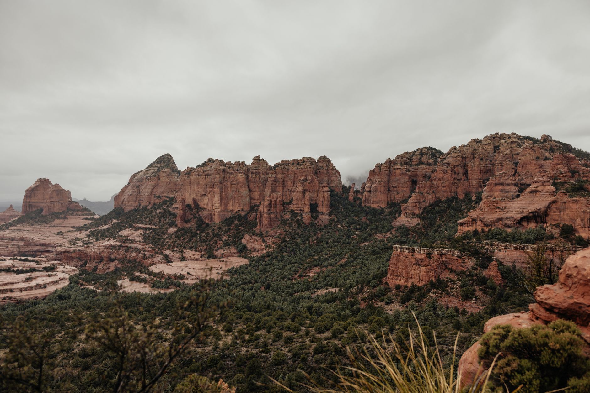 Hikers on the red rock trail below Bell Rock at golden hour, Sedona, surrounded by juniper and desert scrub