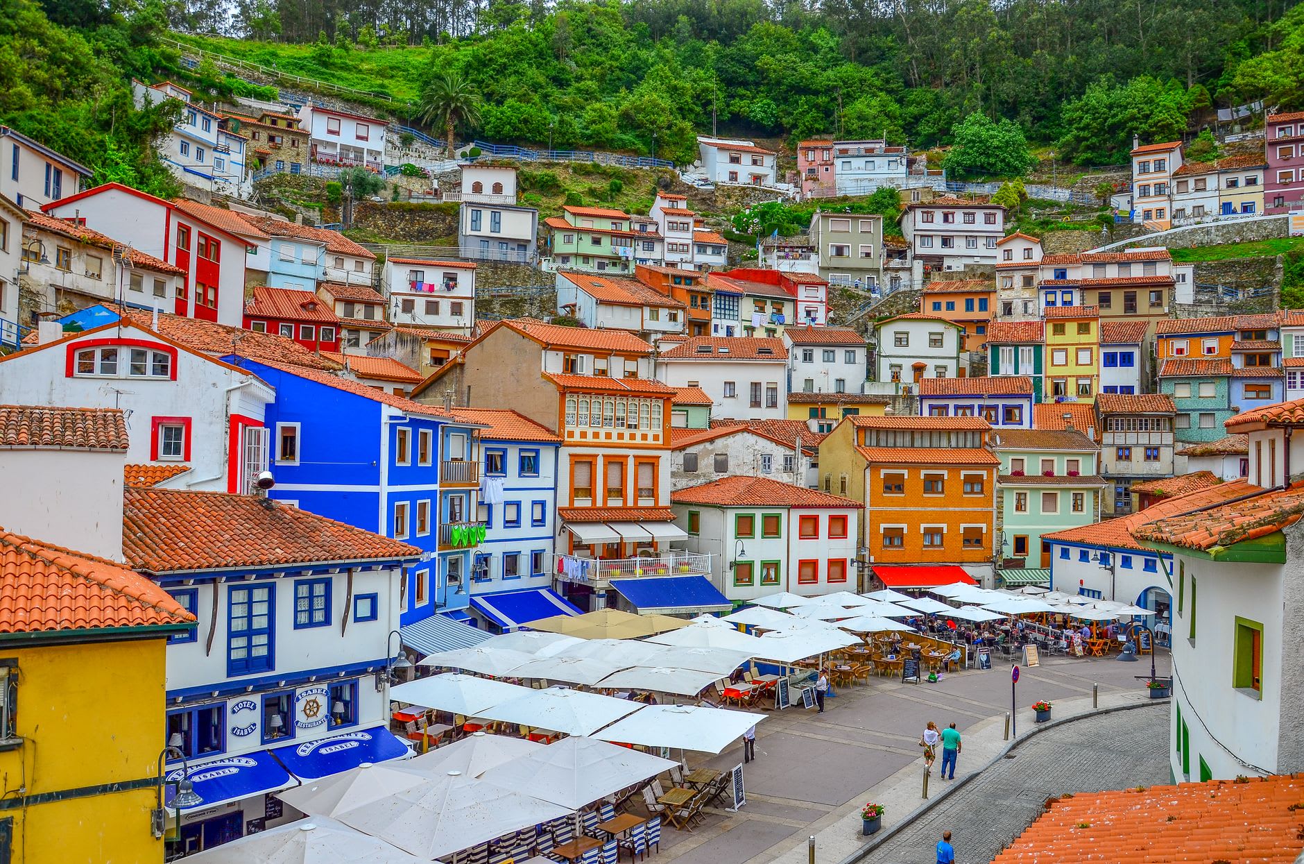 Colorful Cudillero house facades in faded blues and whites reflected in the harbor at low tide
