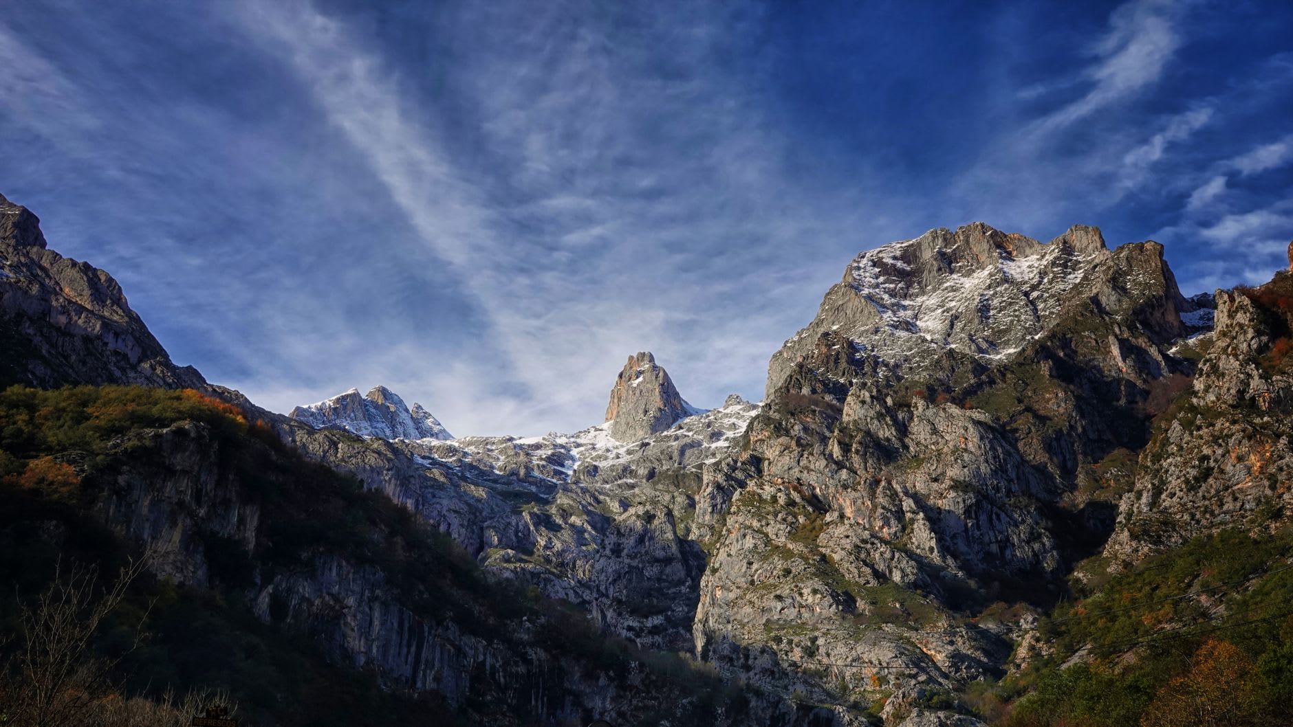 A traditional braña — stone summer hut — on an open mountain slope in Somiedo with the valleys far below
