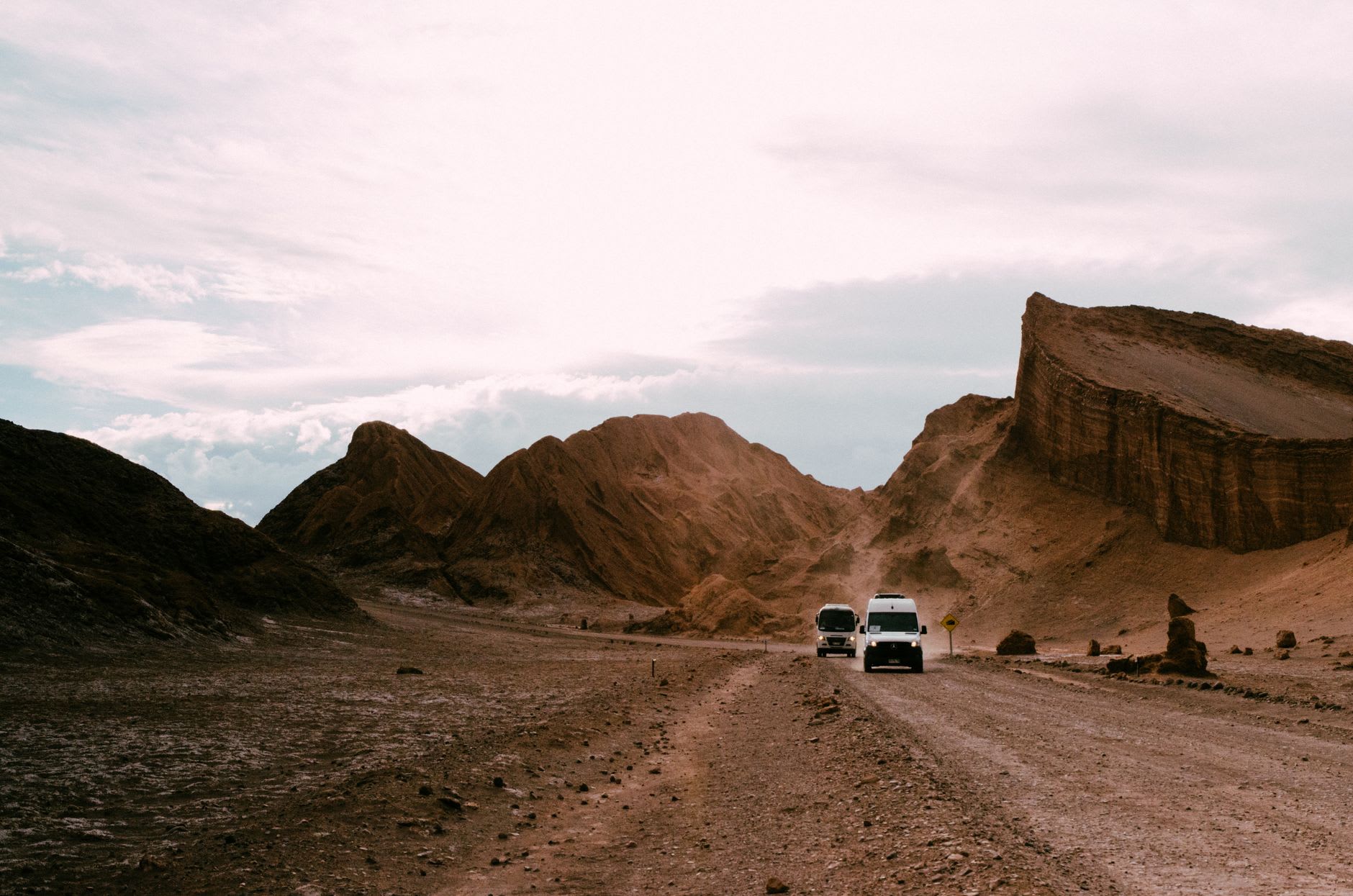 Eroded volcanic rock formations in the Valle de la Muerte rising from red sand in the afternoon glare