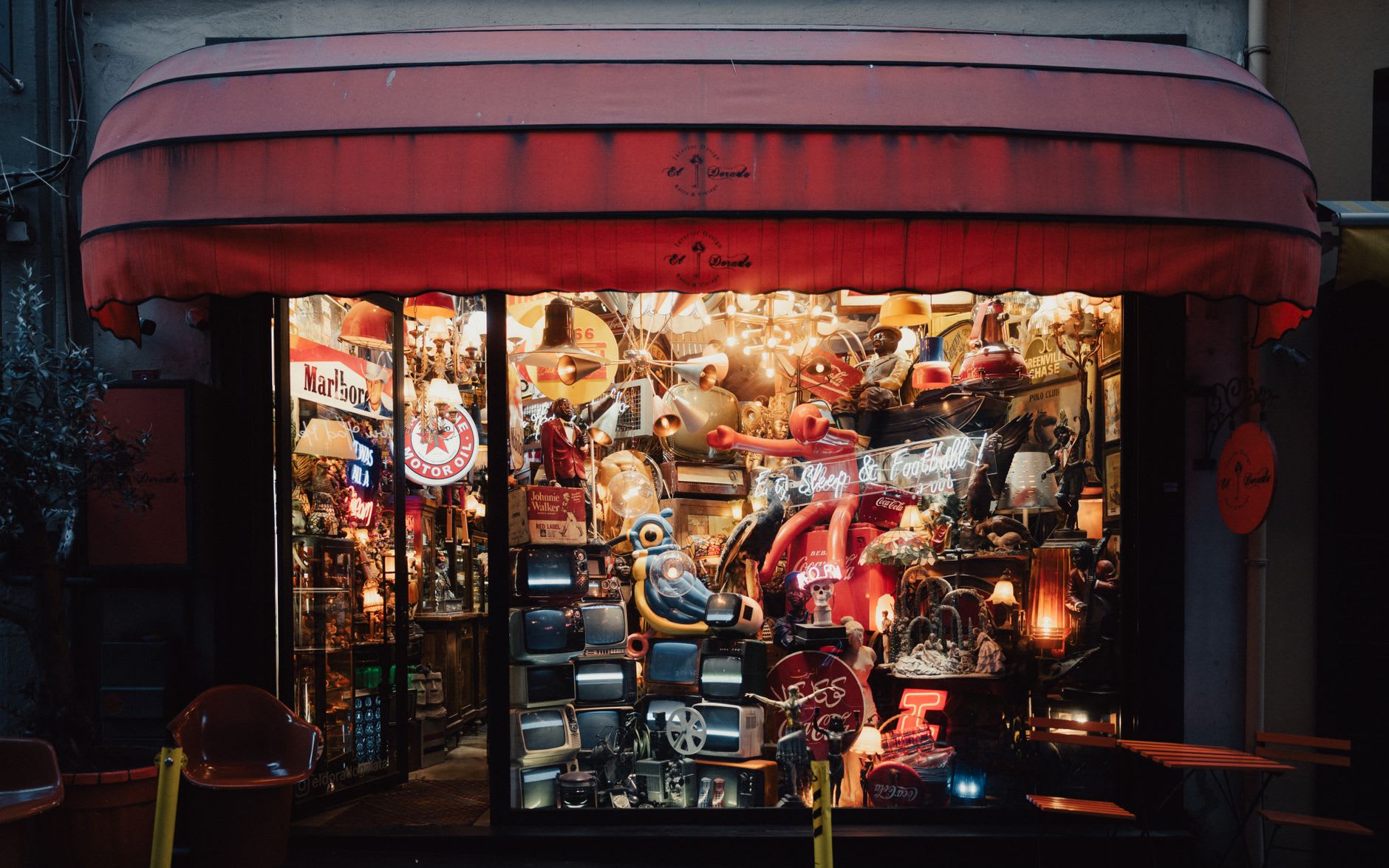 A weathered art deco shopfront on Katoomba Street at dusk, the footpath lit by warm interior light from cafes and bookshops