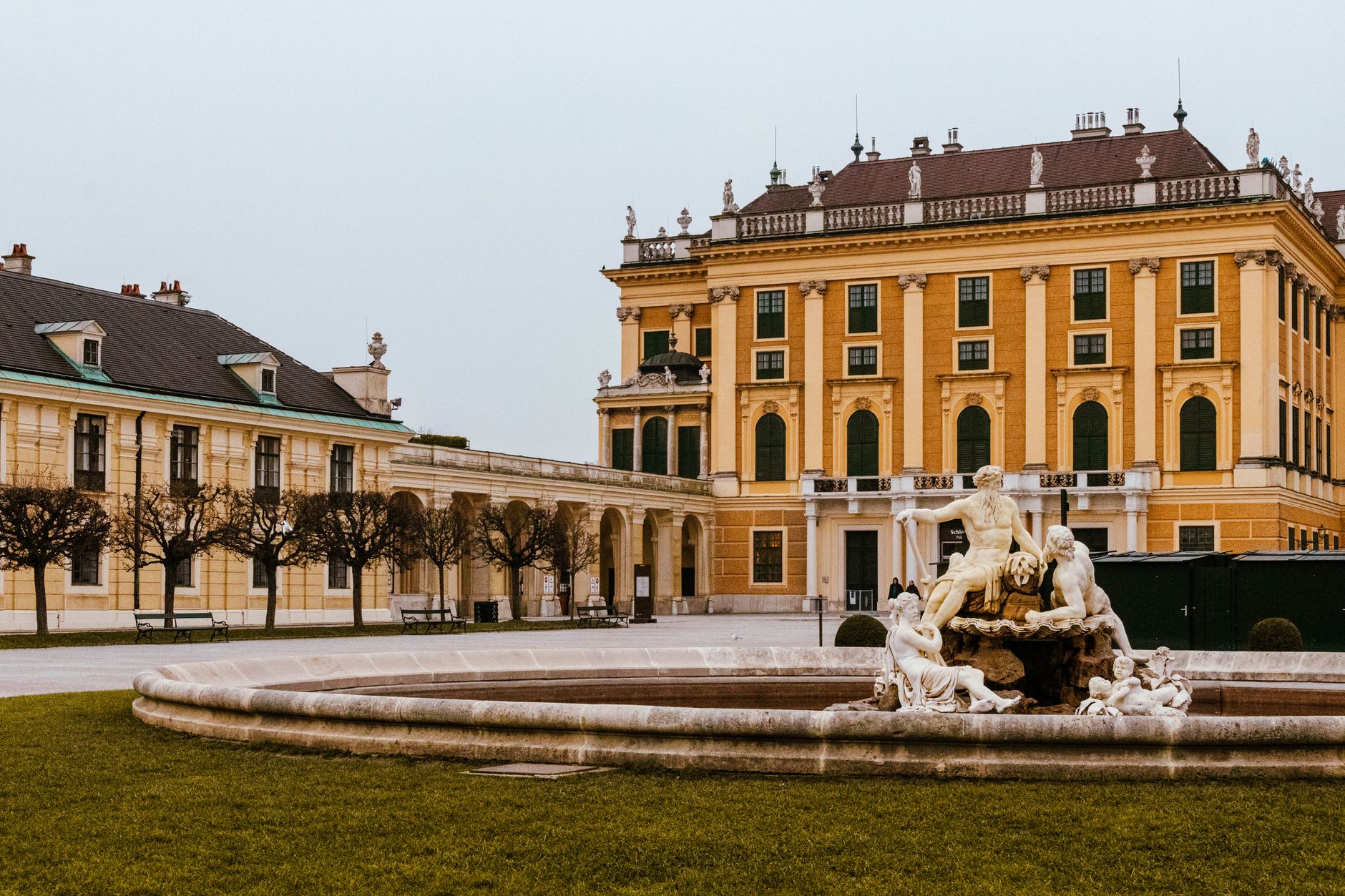 Baroque archways and ochre facades on the Alter Platz, the Lindwurm fountain visible in the soft afternoon light