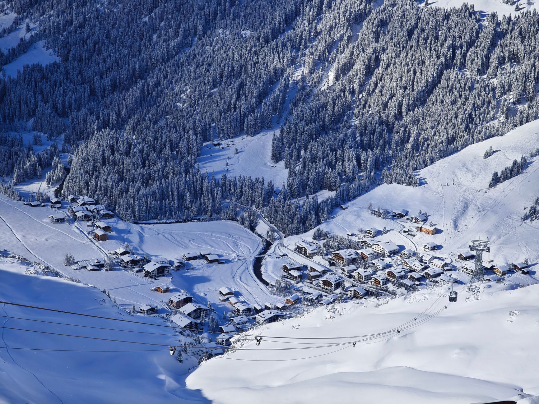 A crowded sunlit après-ski terrace in St. Anton with people in ski gear raising glasses