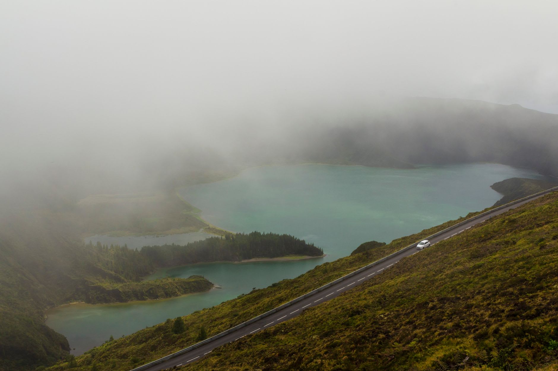 Black volcanic sand beach at the edge of Lagoa do Fogo, cold clear water and green crater walls