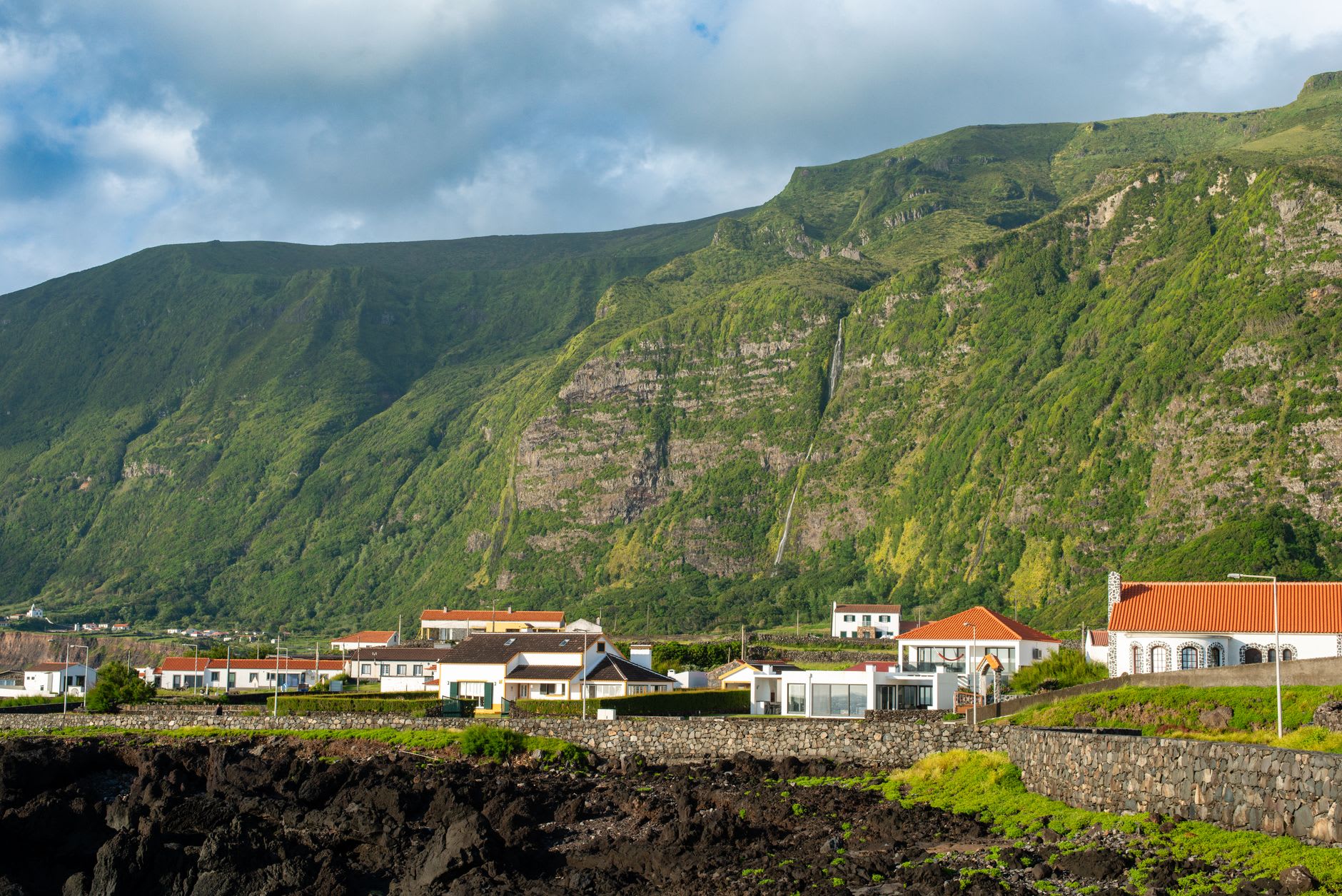 A clear turquoise bay at São Lourenço ringed by terraced vineyards on steep green slopes