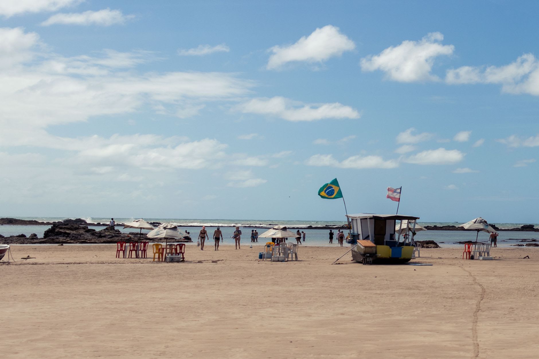 A wide empty beach at Caraíva where the river meets the Atlantic, with calm water on one side and surf on the other