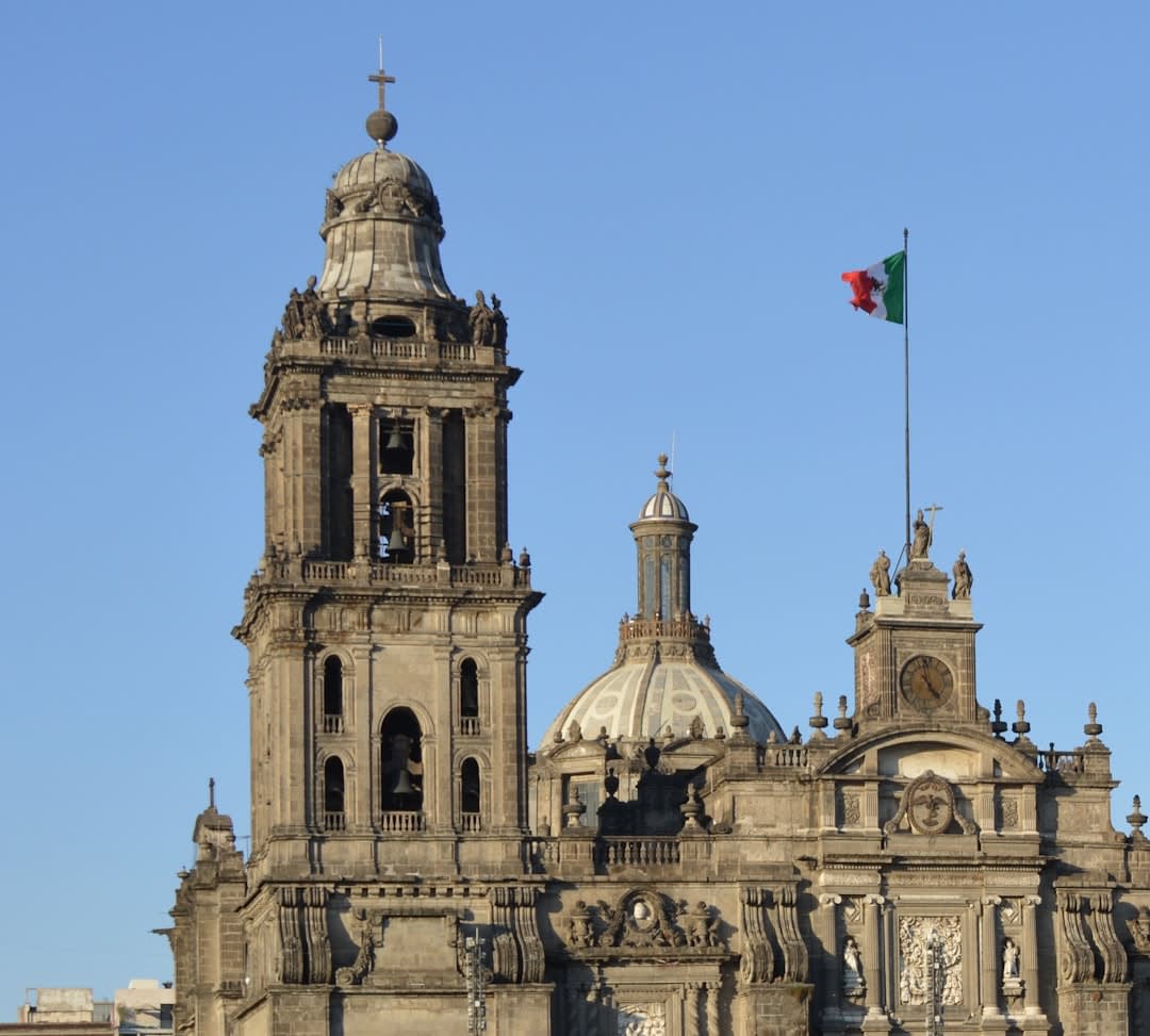 The baroque stone facade of Misión San Javier with its bell tower catching afternoon light, palm trees visible at the edges