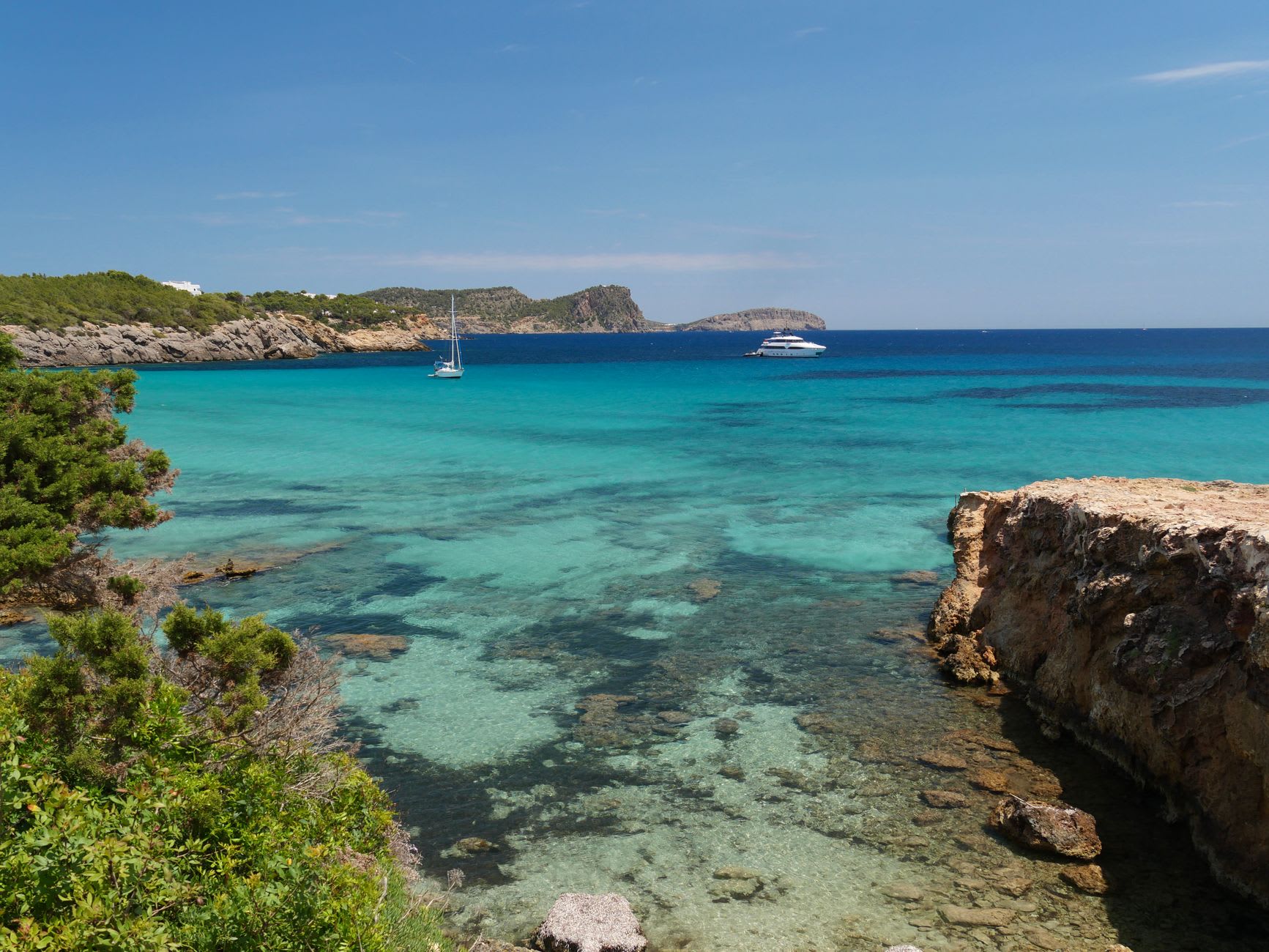 Cala Macarelleta, la cala adyacente más pequeña, agua clara y arena blanca entre dos cabezos de caliza