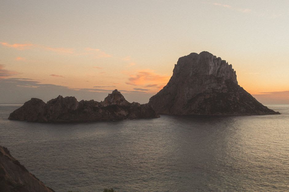 Es Vedrà islet silhouetted against an orange sunset sky from Cala d'Hort