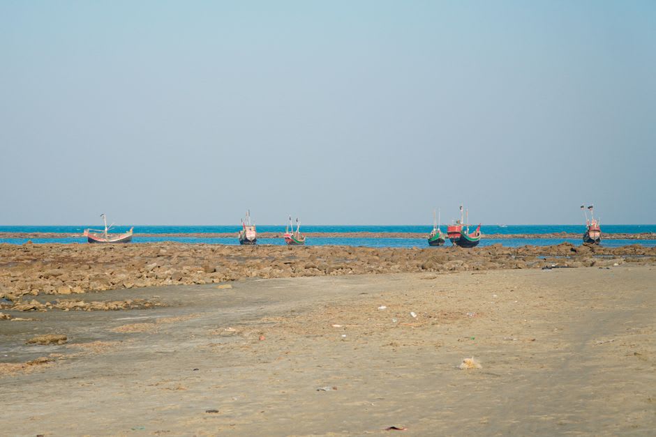 Fishing boats pulled up on the wide sand at Kuakata beach at low tide