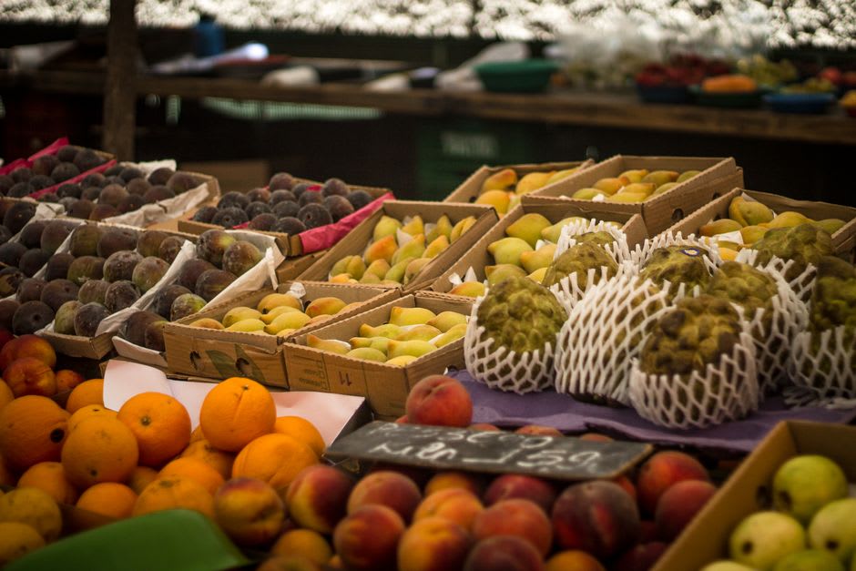 Des caisses de pêches et de figues fraîches empilées à un étal de fruits le long de la rue principale du marché de Qab Elias