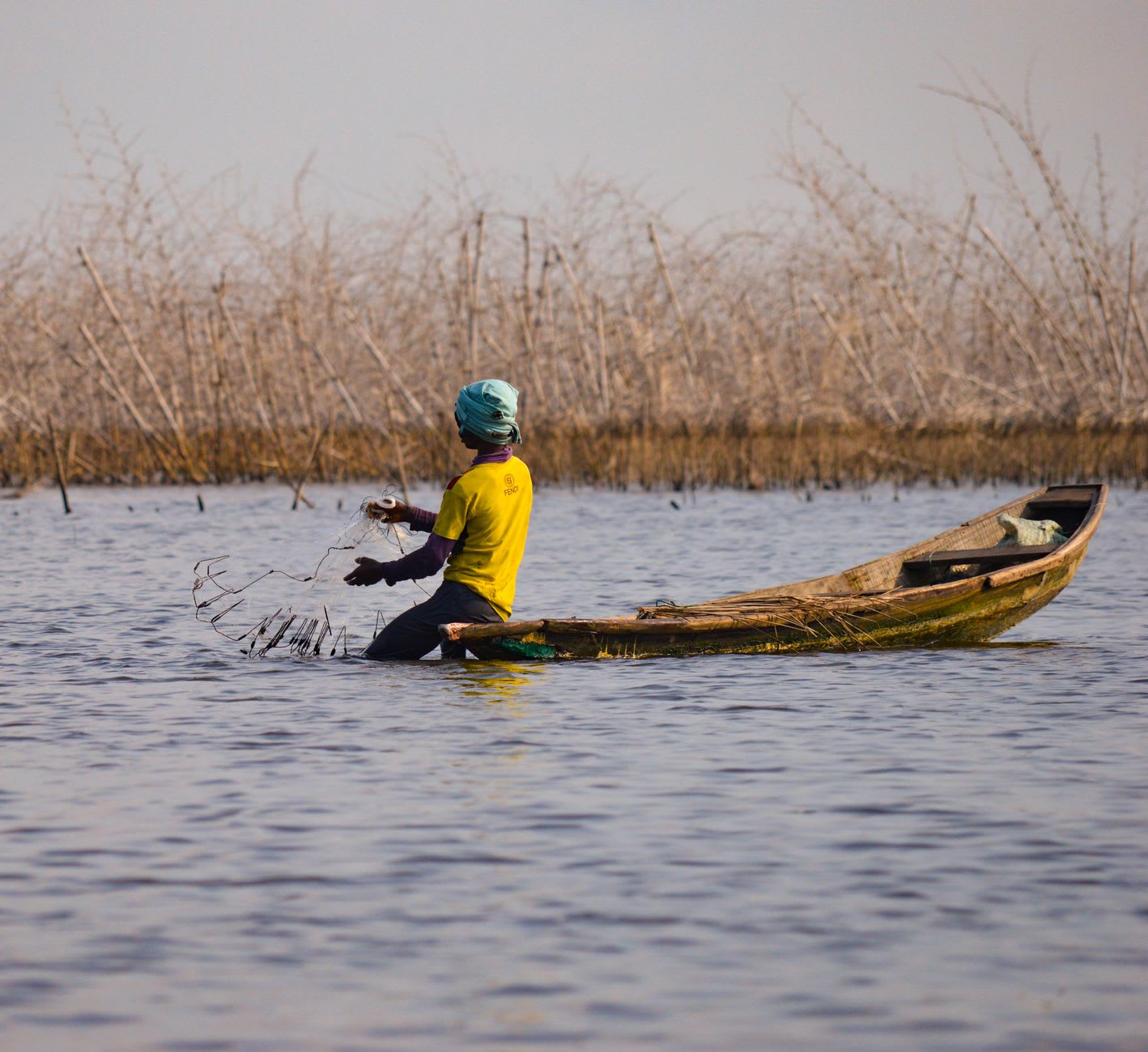 A woman paddling a dugout canoe through the floating market of Ganvié at early morning